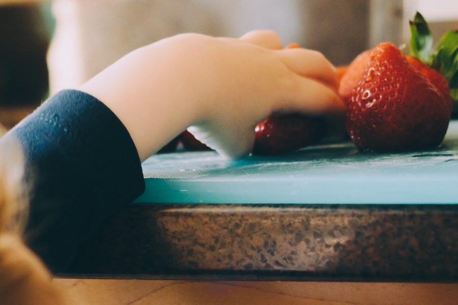 child stealing strawberry off counter