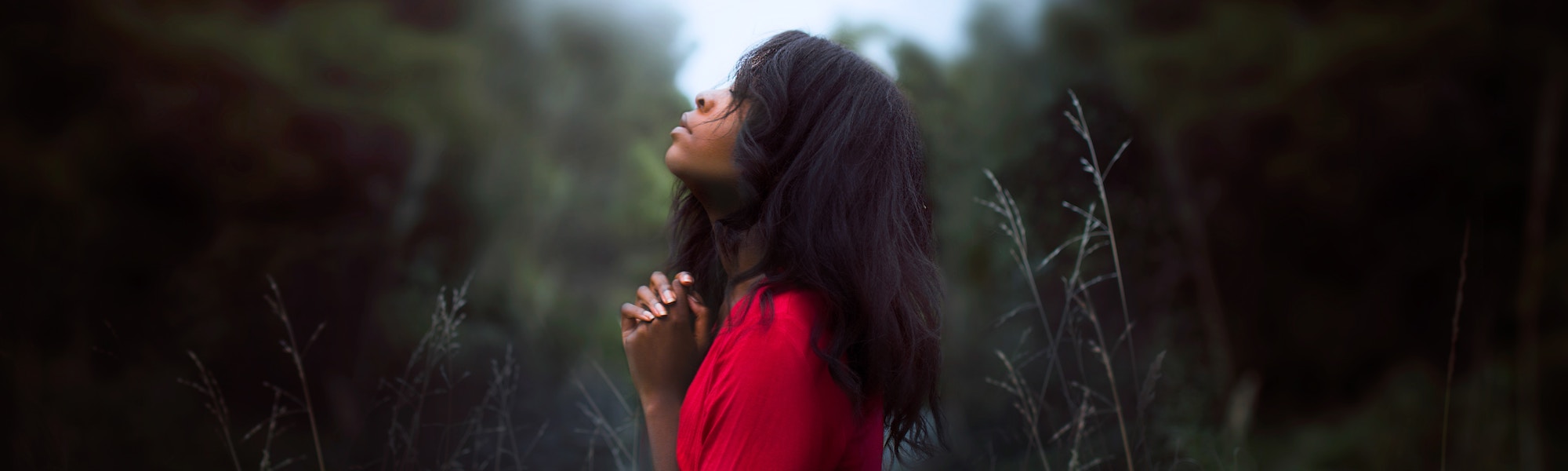 Woman standing amongst trees praying illustrating transforming your prayer life