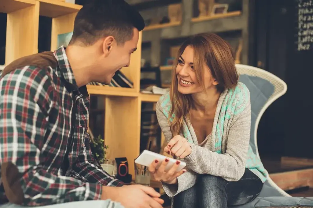 Young woman showing smart phone to a man in a cafe